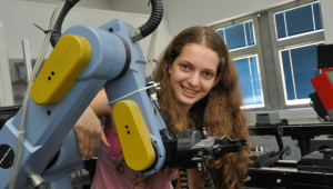 נערה מתכנית מדעני העתיד במעבדה ליד זרוע רובוטית